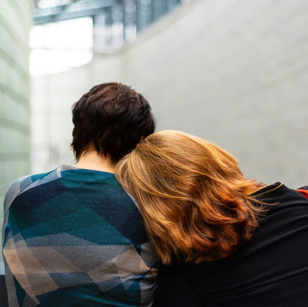 a woman rests her head on another person's shoulder